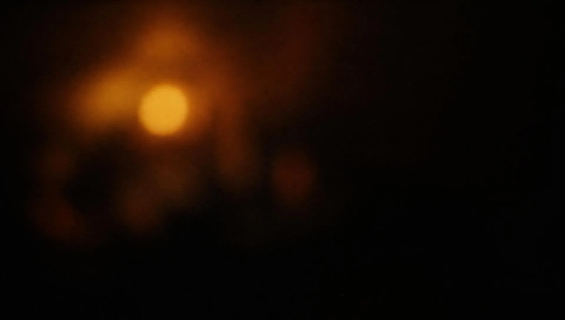 A single warm lamp glowing in deep shadow